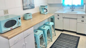 A kitchen with a wooden countertop, a microwave, a coffee maker, and a sink. There are two stools and a rug on the floor. - Cozy Cottage 2BR Queen Families Workers Nurses (Chippewa Lake)