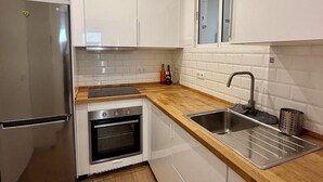 A modern kitchen with white cabinets, a stainless steel refrigerator, an oven, a sink, and a window above the countertop. - Detached house in the center of Santa Cruz de Tenerife (Santa Cruz)
