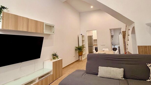 A modern living room with a flat-screen TV, wooden cabinets, a grey sofa, and a kitchen area in the background. - Detached house in the center of Santa Cruz de Tenerife (Santa Cruz)