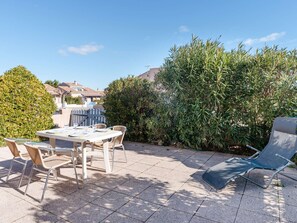An outdoor patio with a table and chairs, surrounded by greenery and a clear sky. - Comfortable House with Pool, Terrace, and Parking in Saint-Pierre-La-Mer (Fleury-Saint-Pierre-la-Mer)