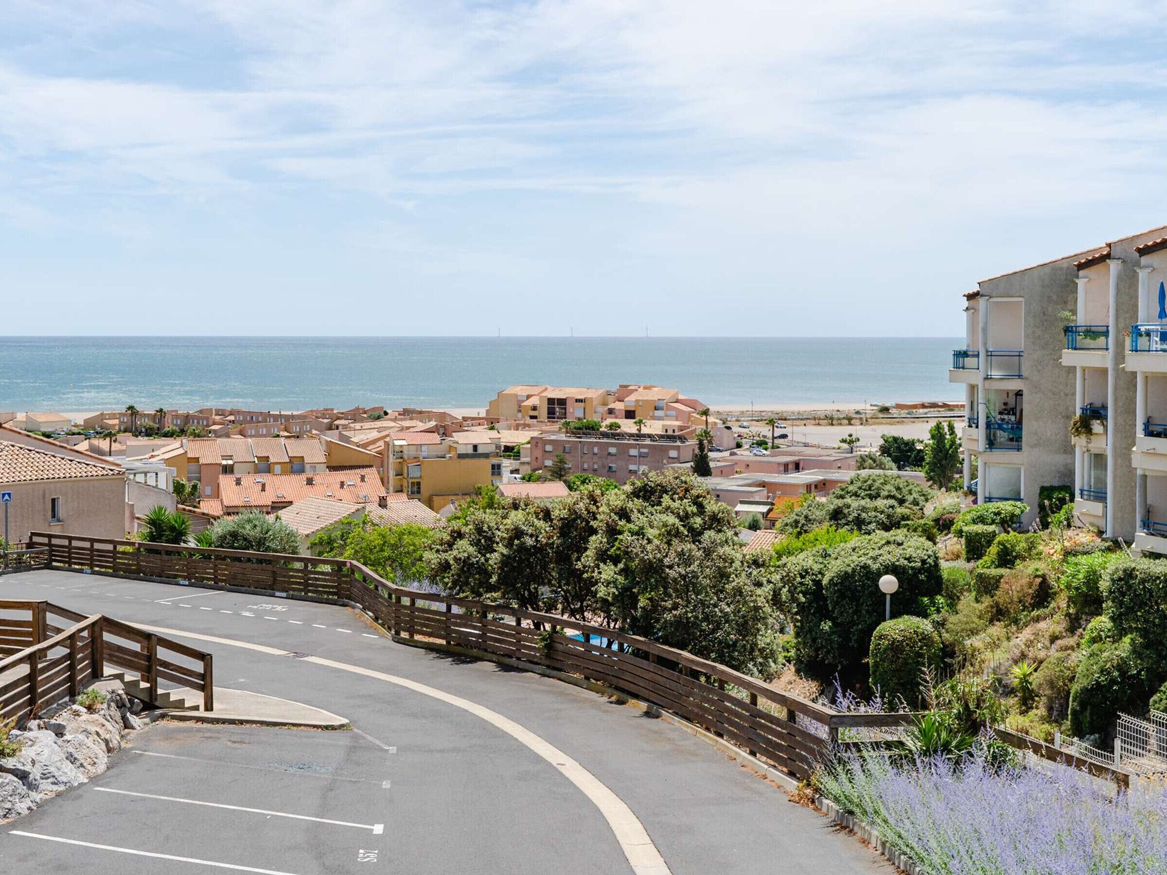 A coastal town with buildings, a beach, and a parking area.
