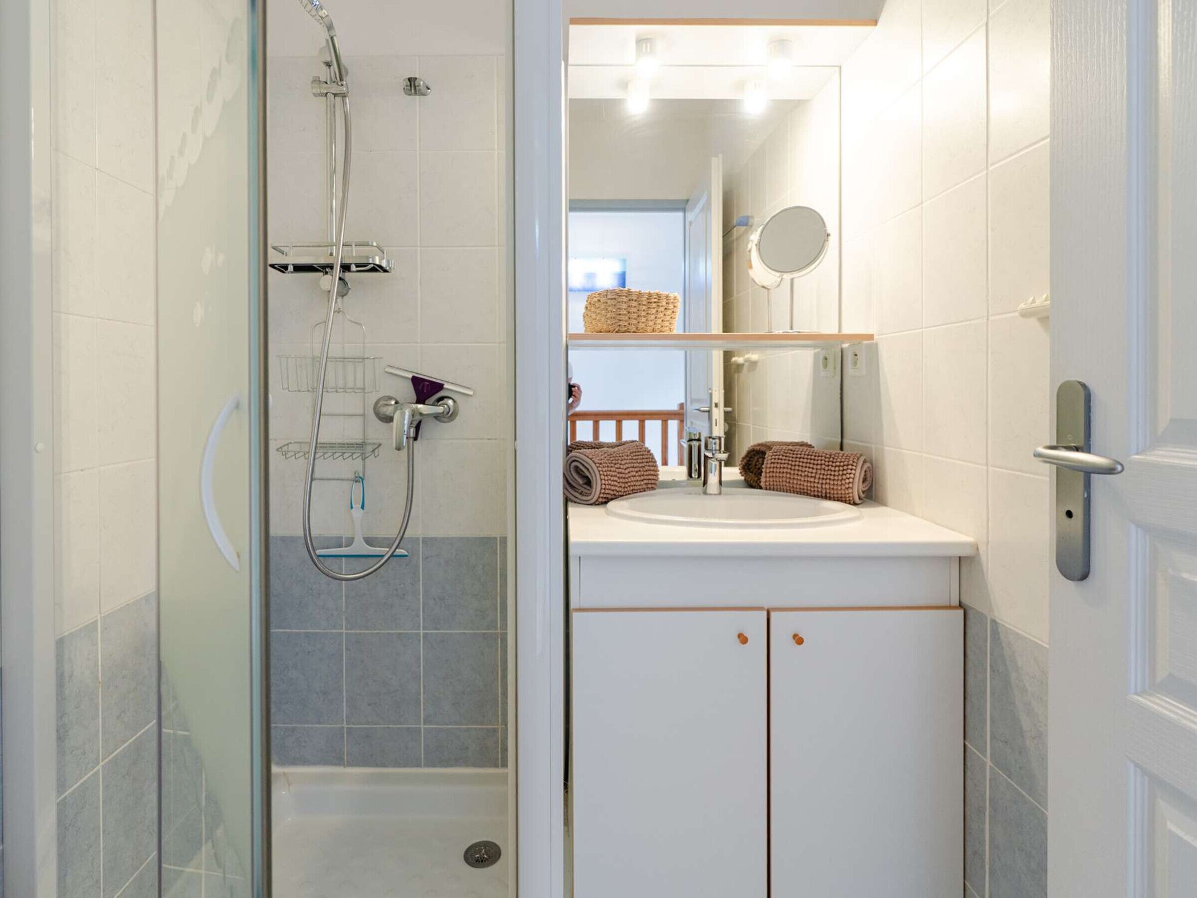 A bathroom with a glass-enclosed shower, a white sink, and a mirror above it.