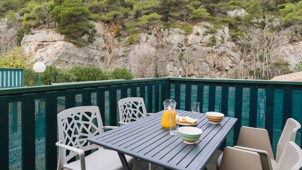 An outdoor dining area with a table and chairs, a bottle of orange juice, and a glass of water. - Air-conditioned apartment with pool - 4 guests (Narbonne)