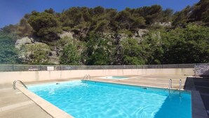 A rectangular pool with clear blue water, surrounded by a concrete deck and metal railings. - Air-conditioned apartment with pool - 4 guests (Narbonne)