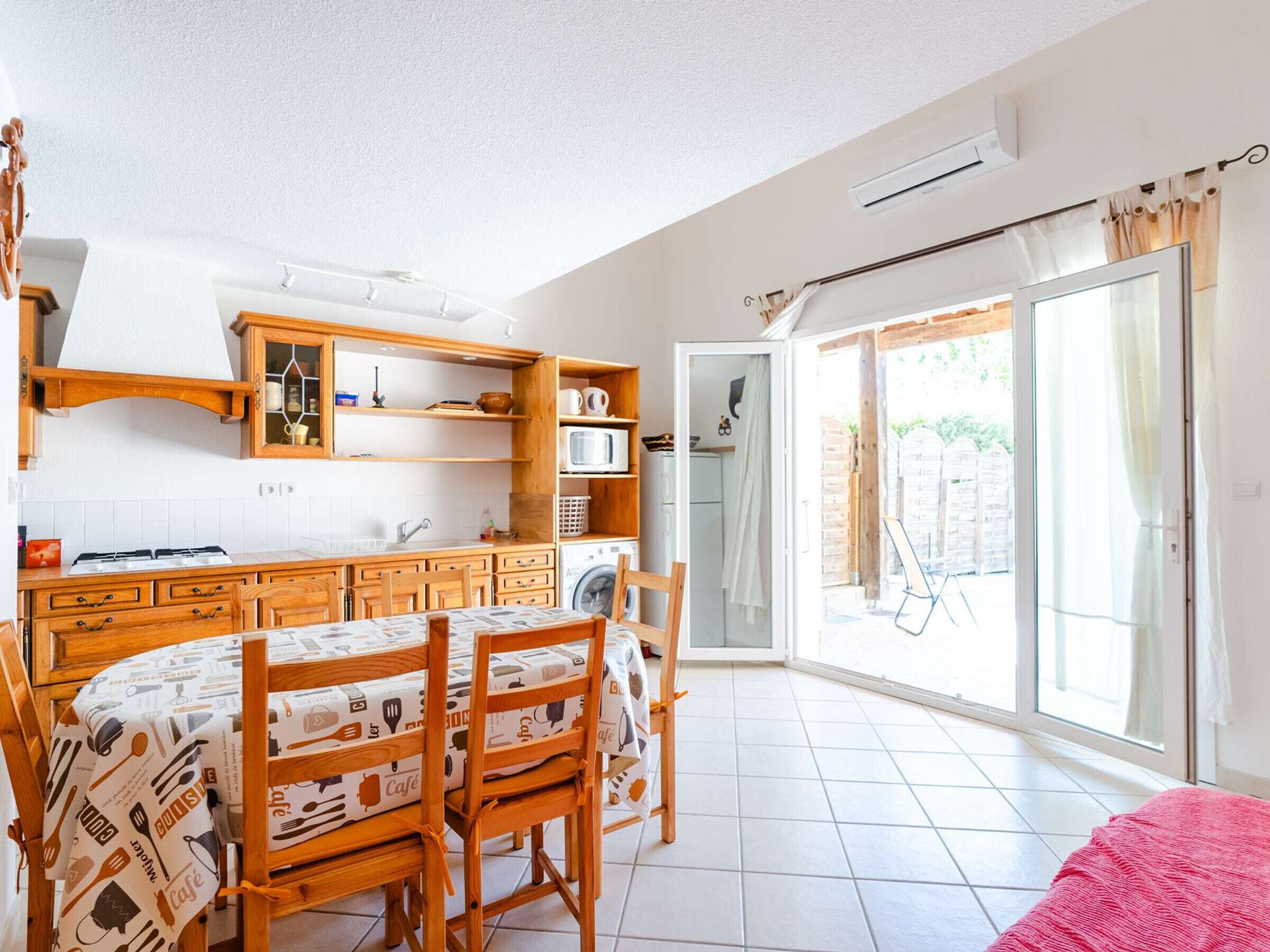 A kitchen with wooden cabinets, a dining table with chairs, a microwave, and a washing machine.