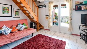 A living room with a red sofa, a wooden staircase, a TV, and a bookshelf.