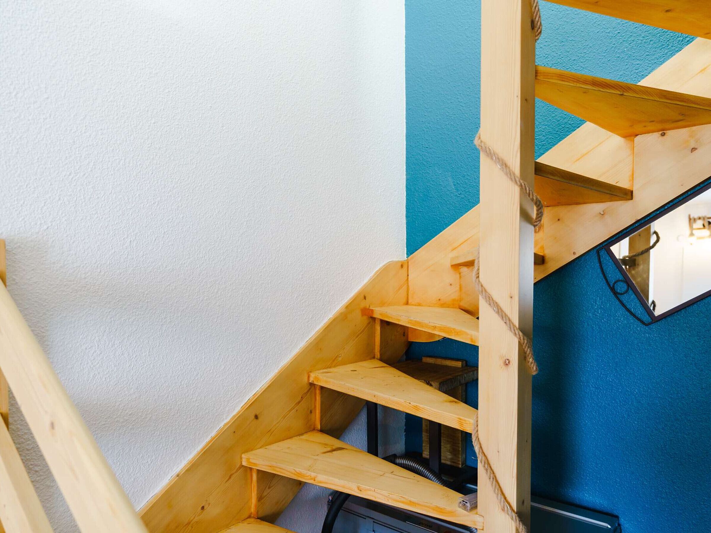 Una escalera de madera con una pared azul y una pared blanca.