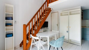 Una habitación con escalera de madera, muebles blancos y televisión.