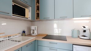 Una cocina moderna con armarios azul claro, un microondas, una cafetera y un lavavajillas.