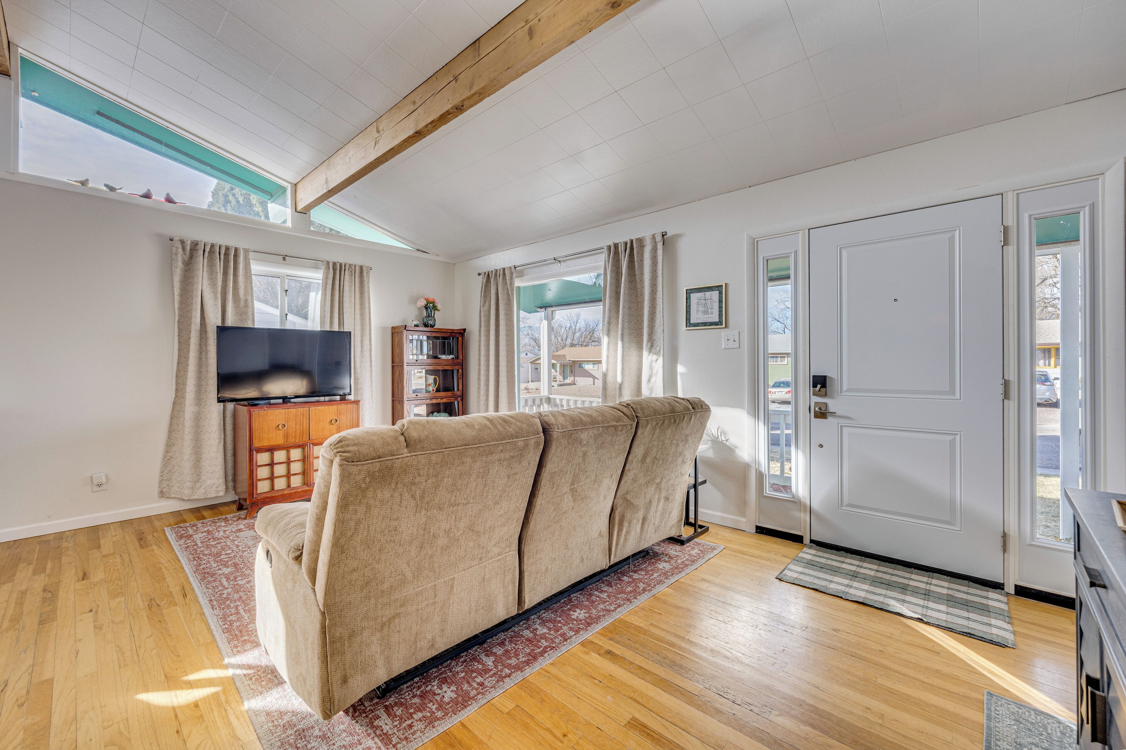 A living room with a sofa, wooden flooring, a television, and a bookshelf.