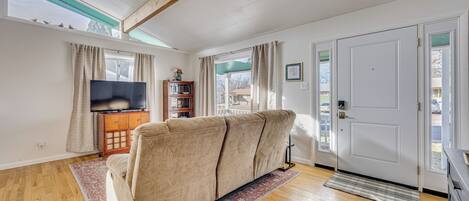 A living room with a sofa, wooden flooring, a television, and a bookshelf.