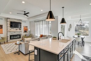 Een moderne keuken met een groot eiland, een inbouwvuurplaats en een eetgedeelte met uitzicht.