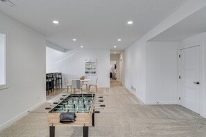 Una camera moderna con un tavolo da calcio, un'area pranzo con sedie e un tavolo, e una porta bianca.