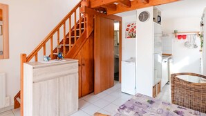 Eine gemütliche Küche mit Holzbalken, einem weißen Kühlschrank und einem Korbwäschekorb.