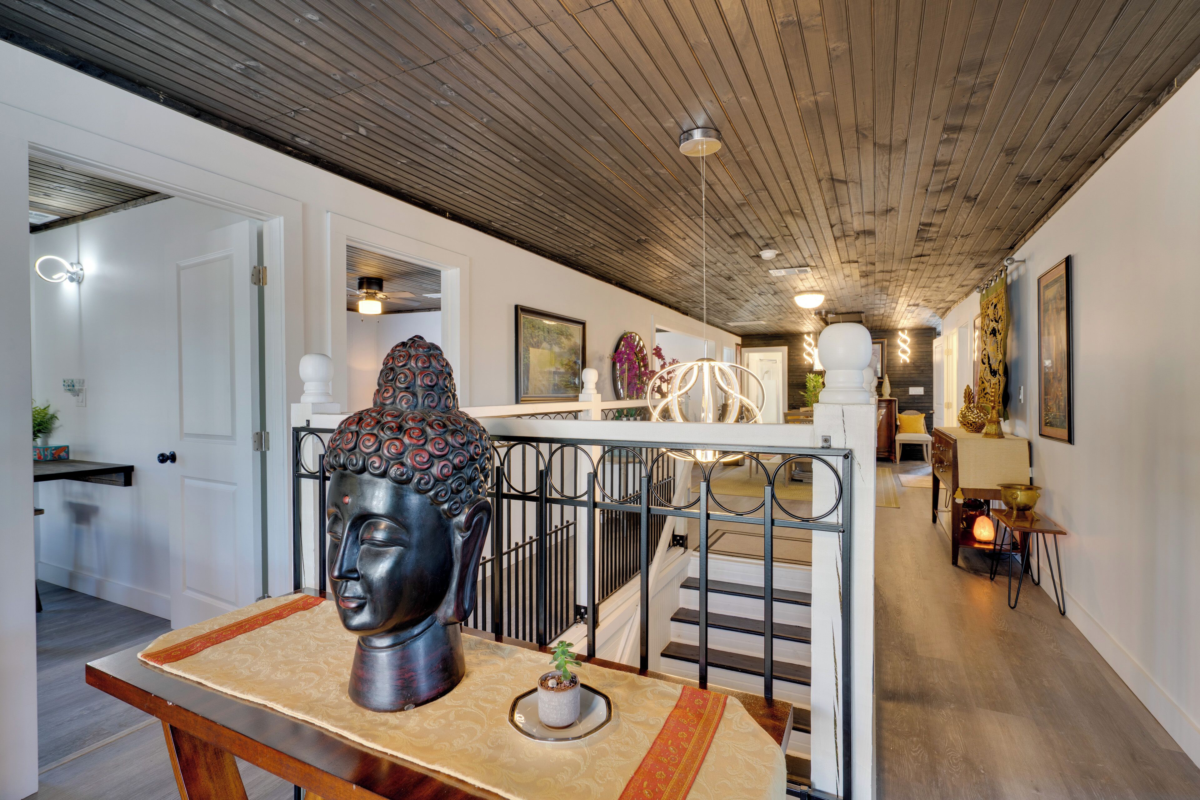 Um interior moderno com uma escadaria, uma escultura de cabeça de Buda e uma parede decorativa.