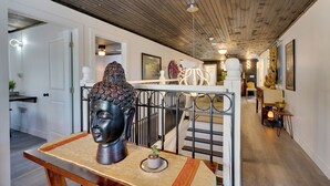 Un interno moderno con una scala, una scultura a testa di Buddha e un pannello decorativo.