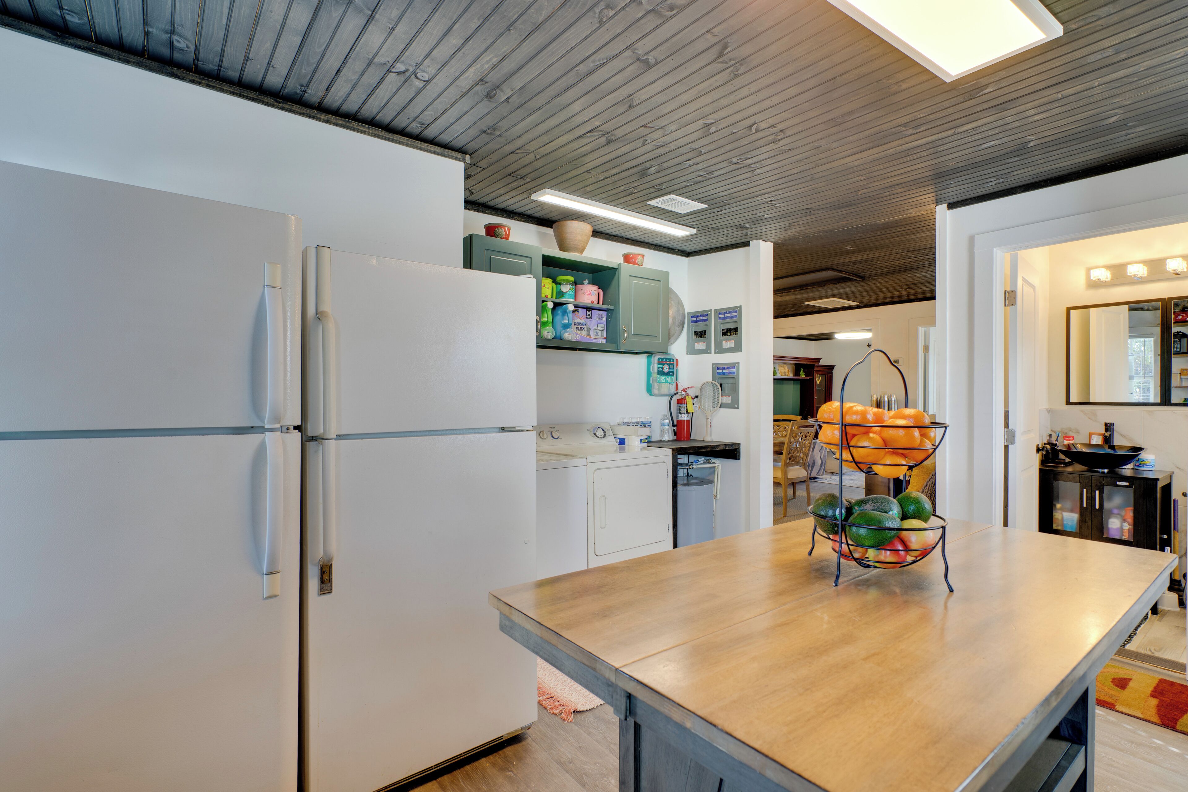 Une cuisine avec des appareils électroménagers blancs, un plan de travail en bois et un panier de fruits.