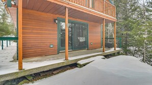 A wooden cabin with a covered porch, a sliding glass door, and a stone foundation. - Riverfront! All-season Base 11 Mi to Sugarloaf Mtn (Kingfield)