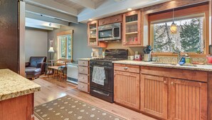 A kitchen with wooden cabinets, a built-in microwave, and a large window overlooking a forest. - Riverfront! All-season Base 11 Mi to Sugarloaf Mtn (Kingfield)