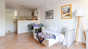 Un ambiente compatto con angolo cottura, zona pranzo e divano.