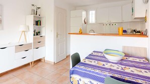 Una cucina compatta con mobili bianchi, un tavolo da pranzo con tovaglia floreale e una sedia.