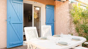Una tavola bianca imbandita per quattro, con persiane blu sullo sfondo.