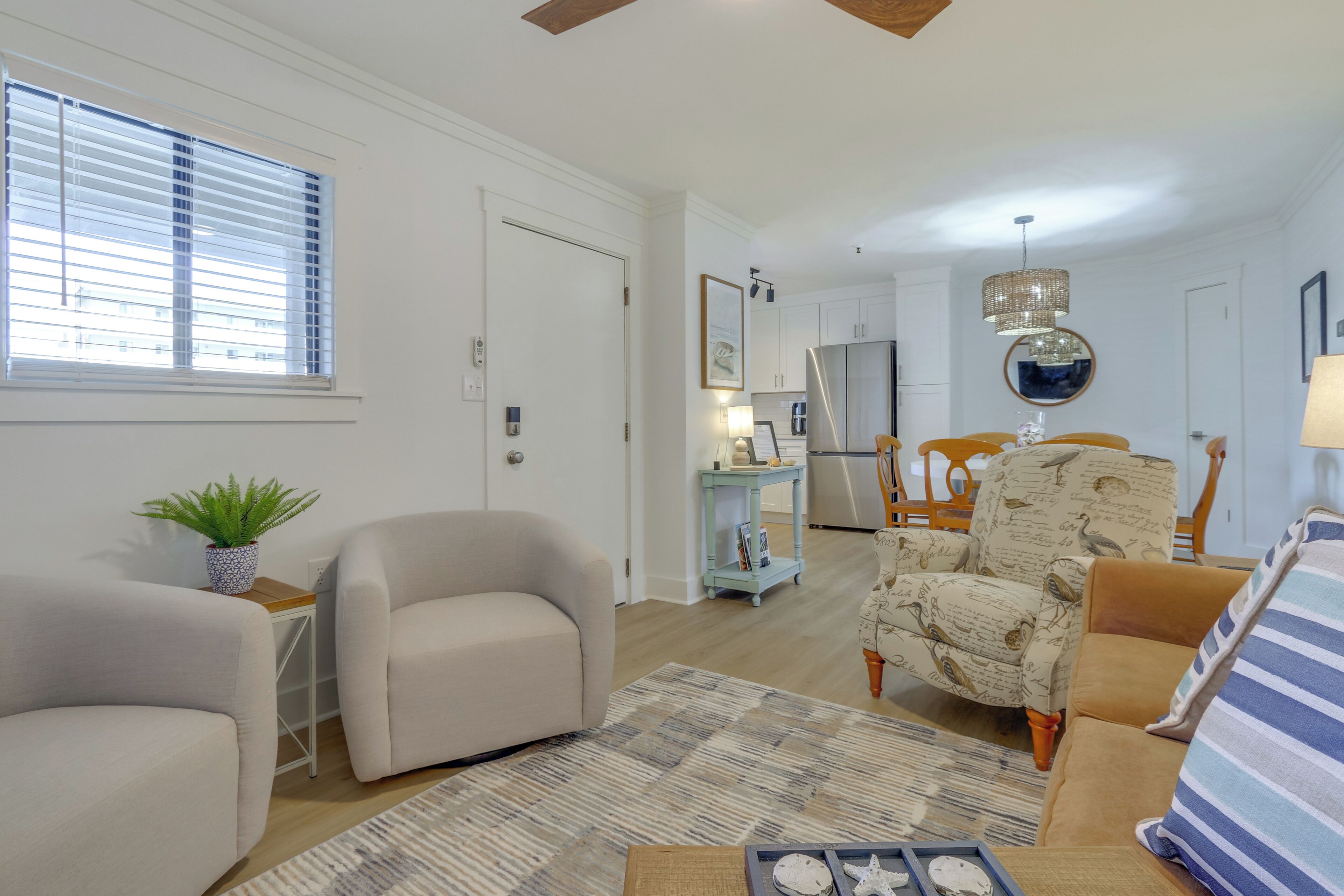 A living room with a sofa, armchair, and a dining area with chairs and a table.