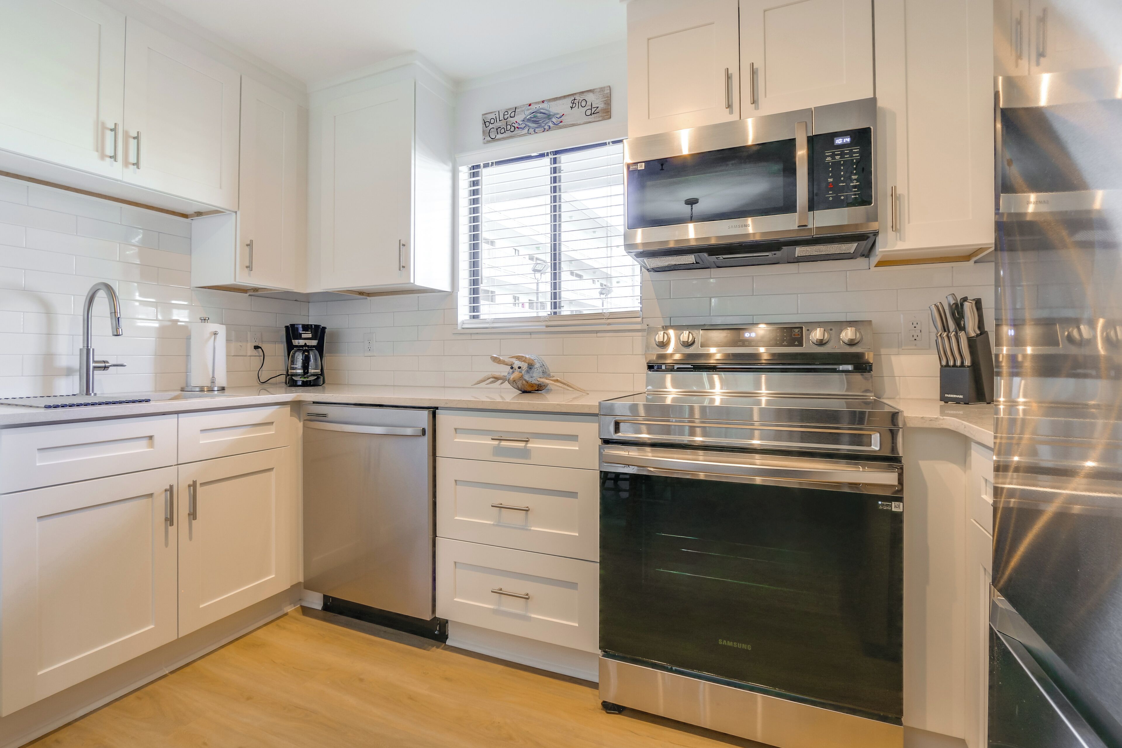 A modern kitchen with white cabinets, stainless steel appliances, and a built-in oven.