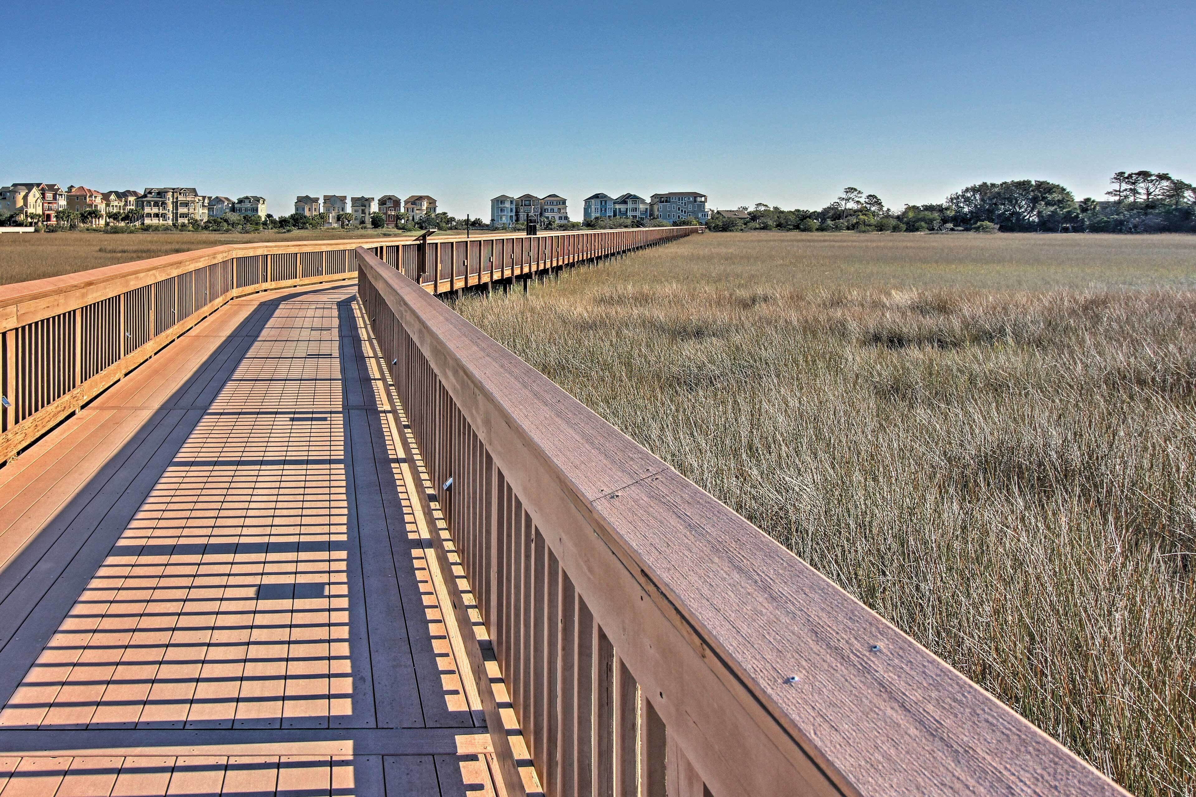 Una passerella di legno che conduce a una spiaggia, con vista chiara su edifici residenziali sullo sfondo.