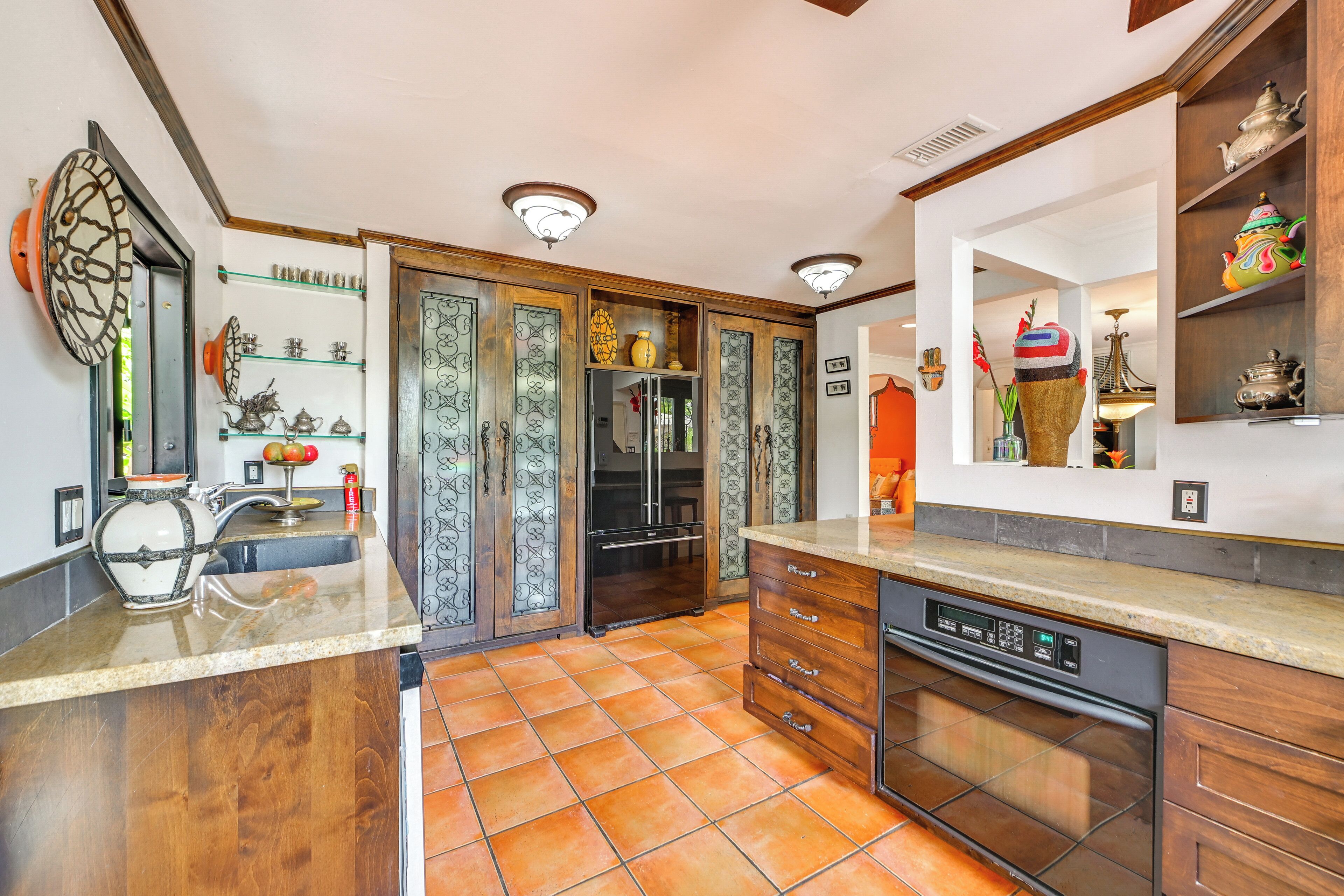 A modern kitchen with a dishwasher, double sink, and decorative items on shelves.
