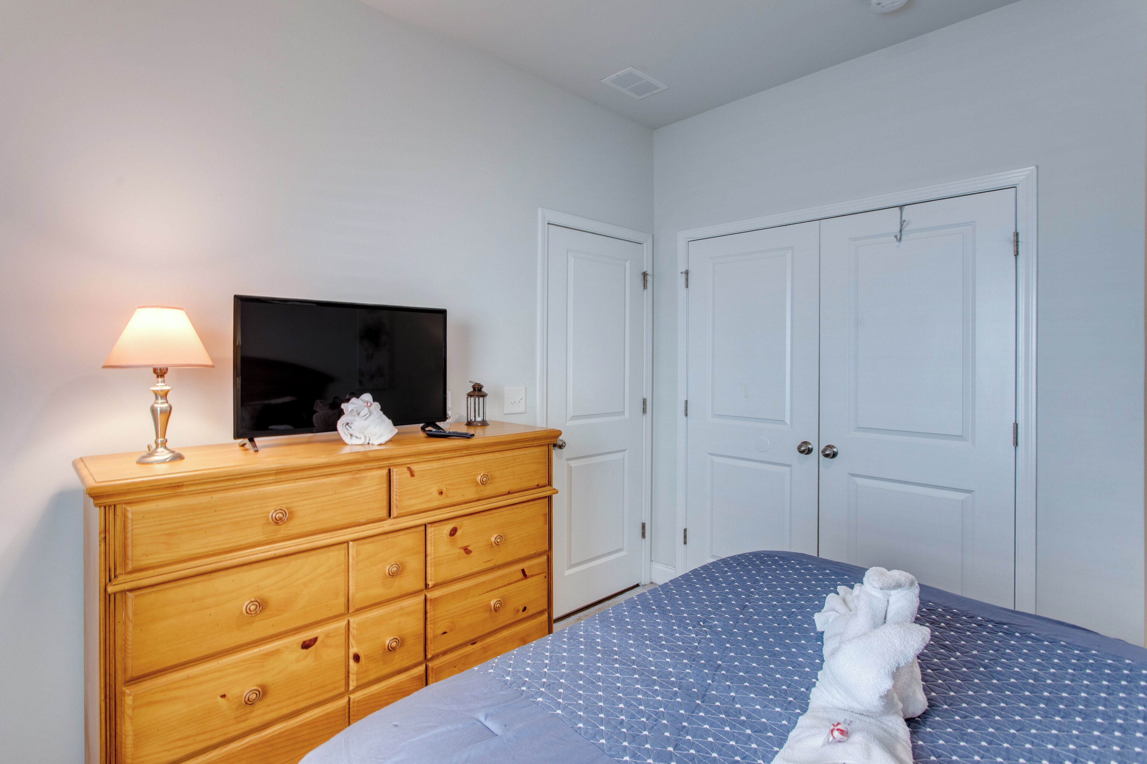 A bedroom with a bed, a dresser, a television, and a door.