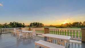 An outdoor patio with white wooden furniture and a view of a golf course at sunset. - Ultimate Golf Resort Getaway in Myrtle Beach! (Myrtle Beach)