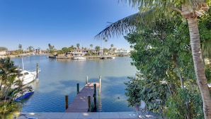 A marina with boats docked, a wooden pier, and a backdrop of houses and palm trees. - 1 Block to Beach! Boutique Condo at Johns Pass (Madeira Beach)