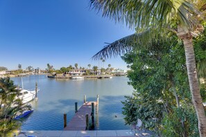 A marina with boats docked, a wooden pier, and a backdrop of houses and palm trees. - 1 Block to Beach! Boutique Condo at Johns Pass (Madeira Beach)