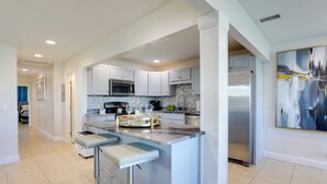 A modern kitchen with a central island, stainless steel appliances, and a marble backsplash. - 1 Block to Beach! Boutique Condo at Johns Pass (Madeira Beach)