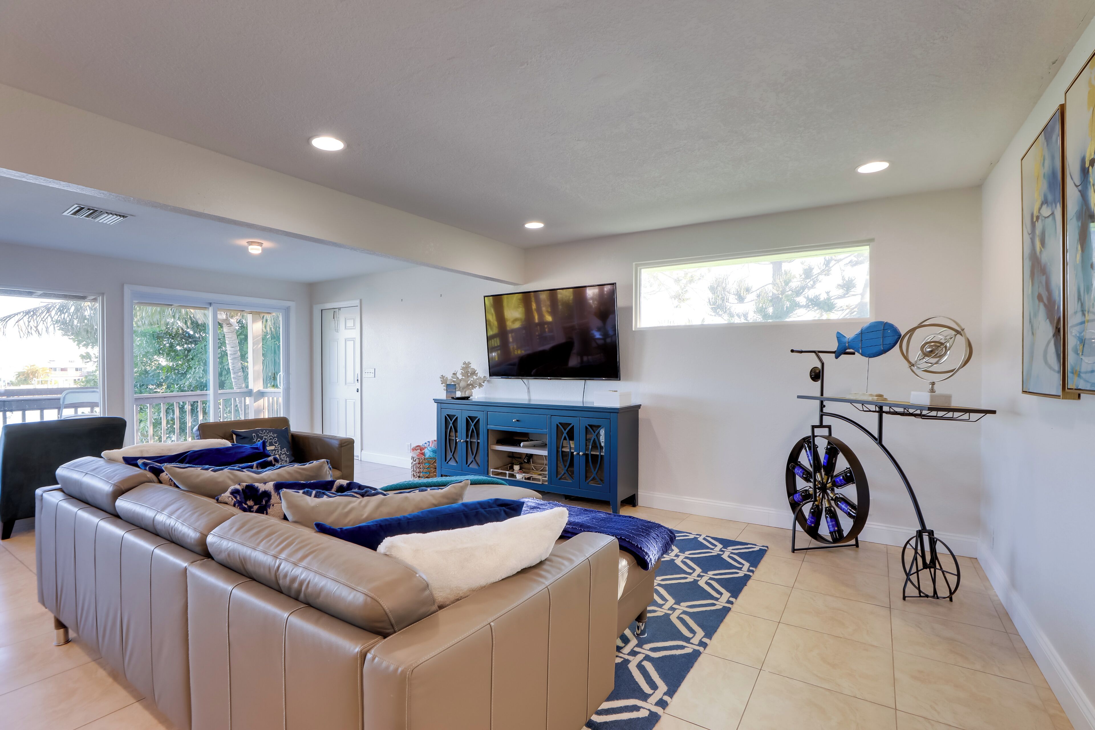 Un salon moderne avec un canapé en cuir, un téléviseur à écran plat, un meuble bleu et une roue décorative.