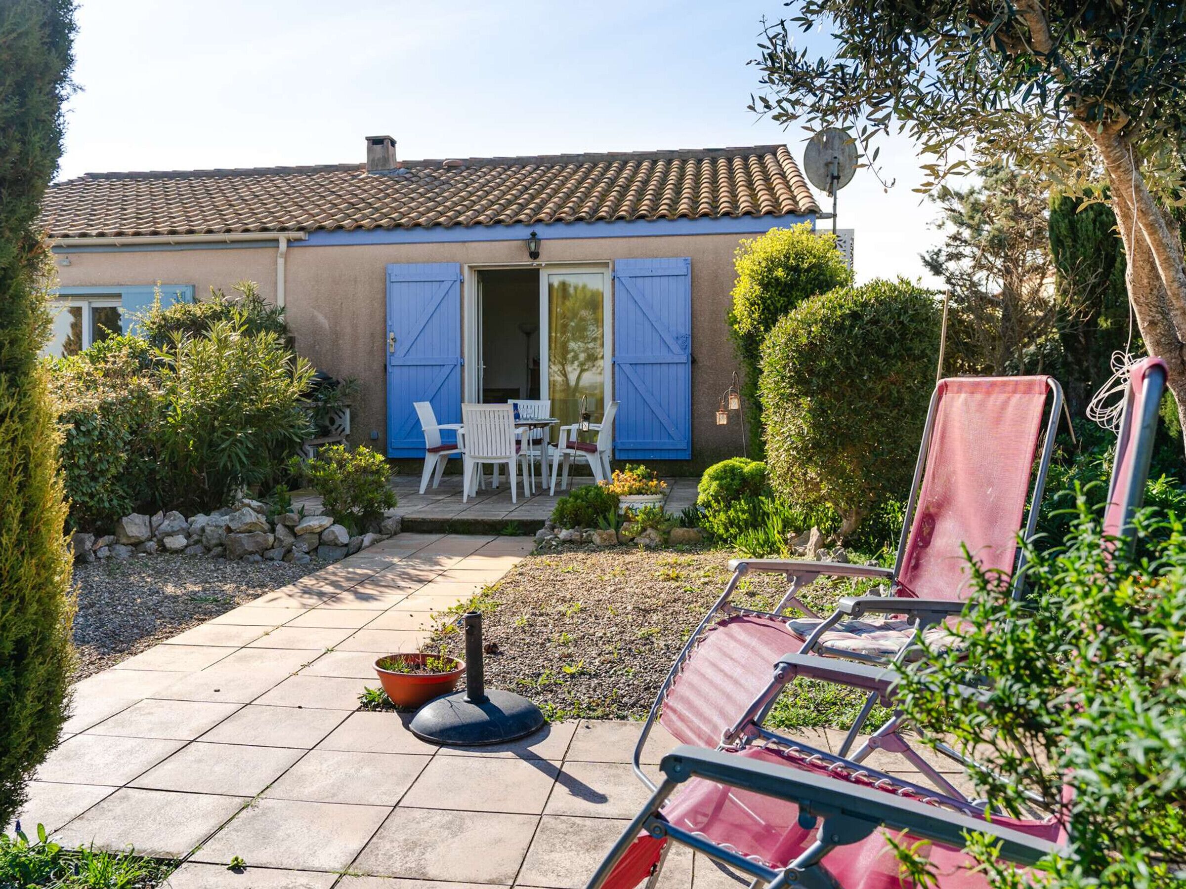 A house with a tiled roof, a blue door, and a patio with chairs and a table.