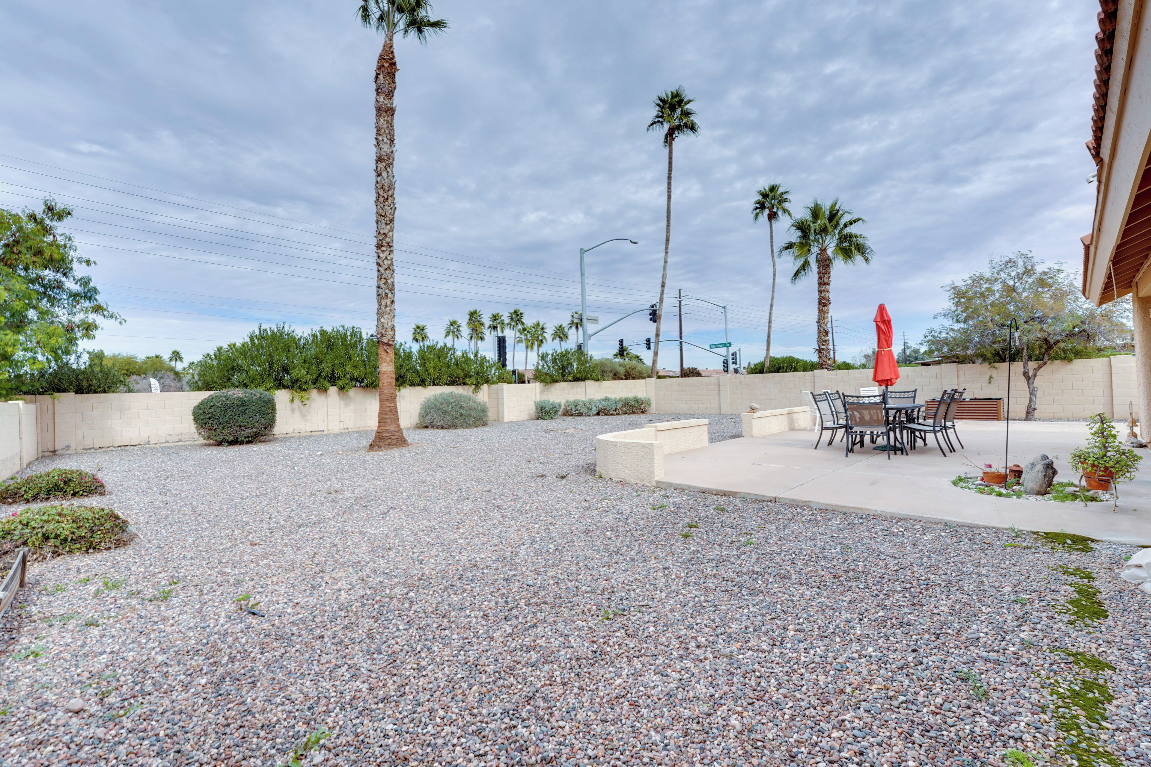 A patio area with a gravel ground, palm trees, and outdoor furniture.