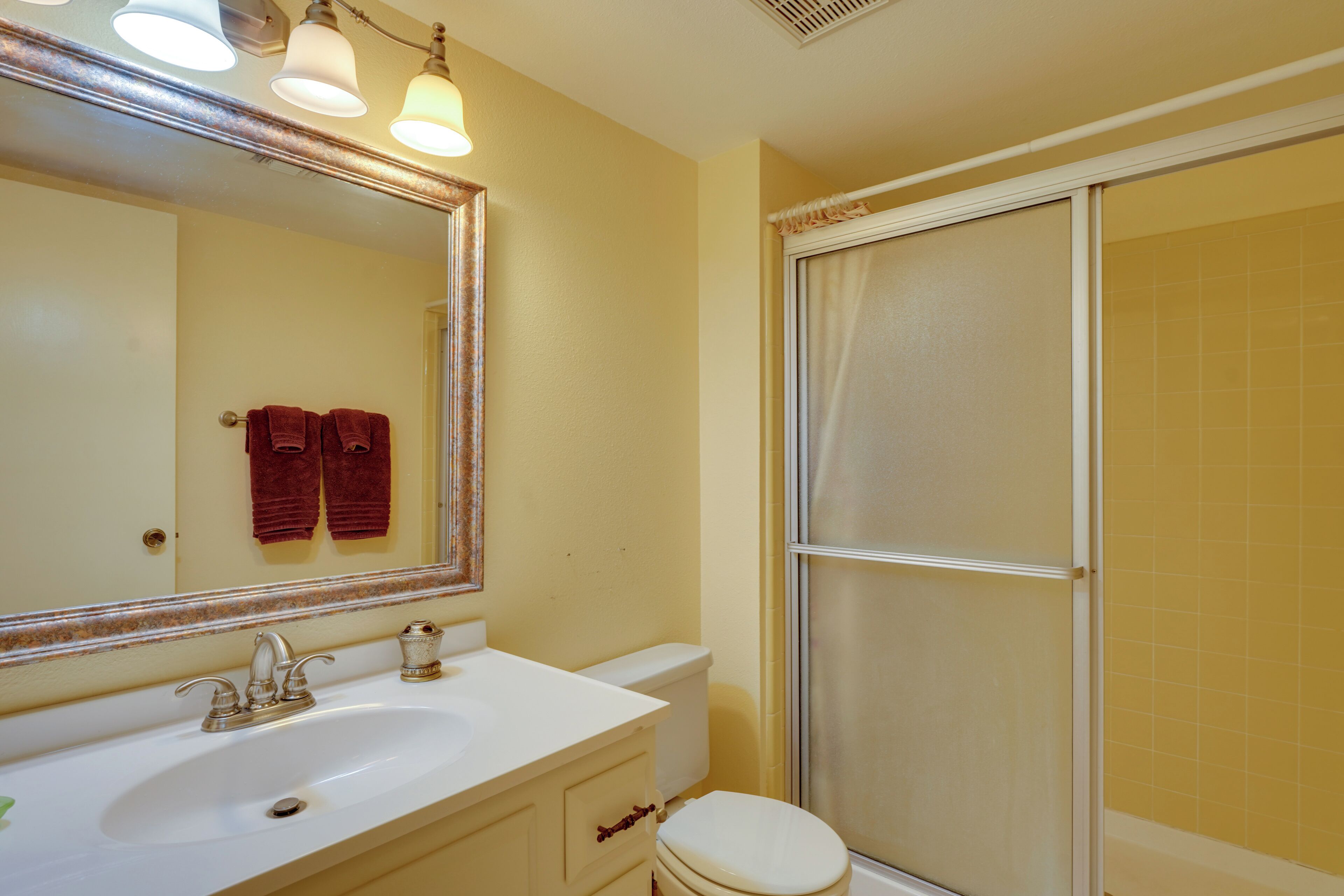 A bathroom with a white sink, a mirror, and a shower enclosure.