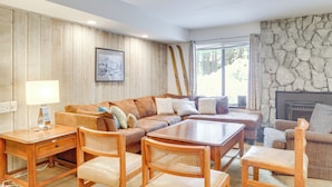 A cozy living room with a wooden panel wall, a stone fireplace, a brown leather sofa, and a wooden coffee table. - 1 Mi to Village & Eagle Lodge! Extended Stay Unit (Mammoth Lakes)