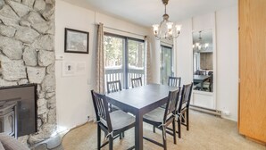 A dining area with a stone wall, a large table, and chairs. - 1 Mi to Village & Eagle Lodge! Extended Stay Unit (Mammoth Lakes)