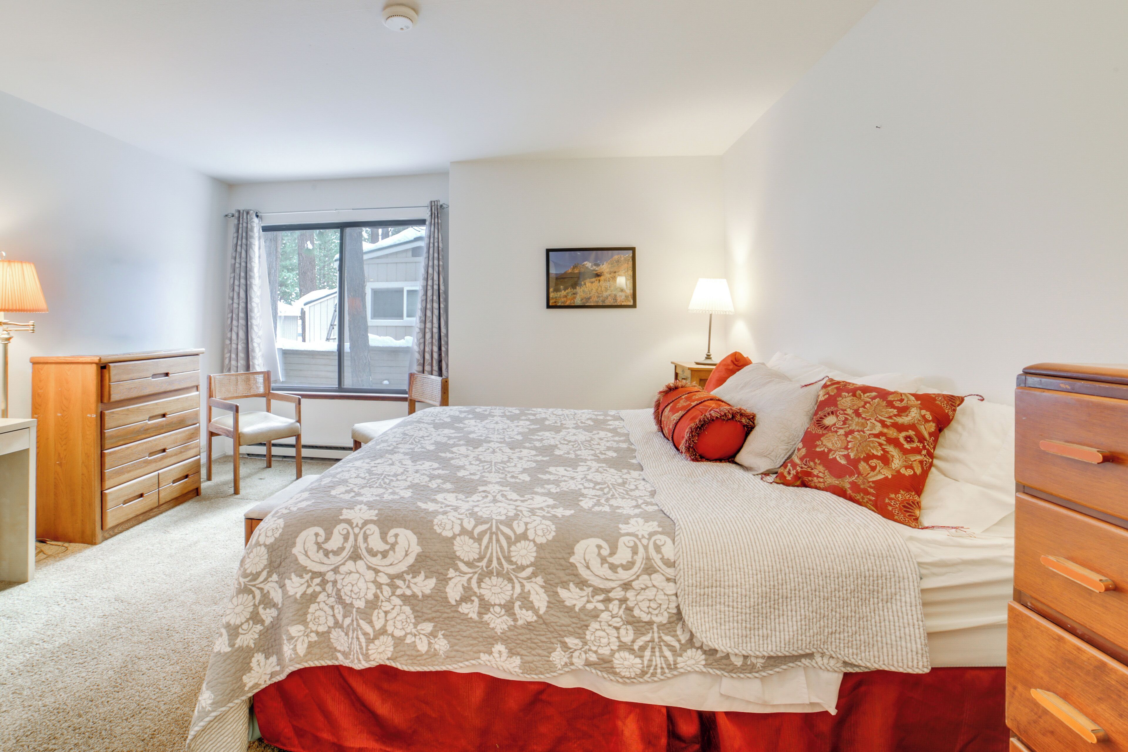 Une chambre à coucher avec un lit, une chaise, une commode et une fenêtre.
