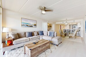 A living room with a sectional sofa, a wooden coffee table, and a ceiling fan. - 2BR w/ Stunning Gulf Views: Suntide III - Unit 902 (South Padre Island)