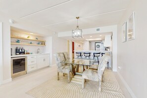 A modern kitchen with white cabinetry, a glass dining table, patterned chairs, and a decorative rug. - 2BR w/ Stunning Gulf Views: Suntide III - Unit 902 (South Padre Island)