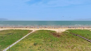 Ein Strand mit einer Rasenfläche und einer Holzpromenade.