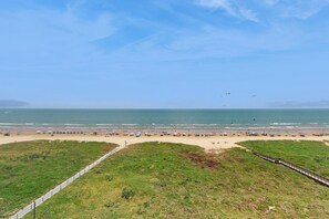 A beach with a grassy area and a wooden walkway. - 2BR w/ Stunning Gulf Views: Suntide III - Unit 902 (South Padre Island)