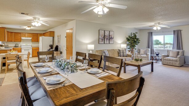 A spacious living area with a dining table set for six, wooden furniture, ceiling fans, and a view of the outdoors. - Yard, Patio & Grill! Florence Home Near Monastery (Florence)