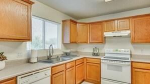 A kitchen with wooden cabinets, a dishwasher, a stove, and a window with blinds. - Yard, Patio & Grill! Florence Home Near Monastery (Florence)