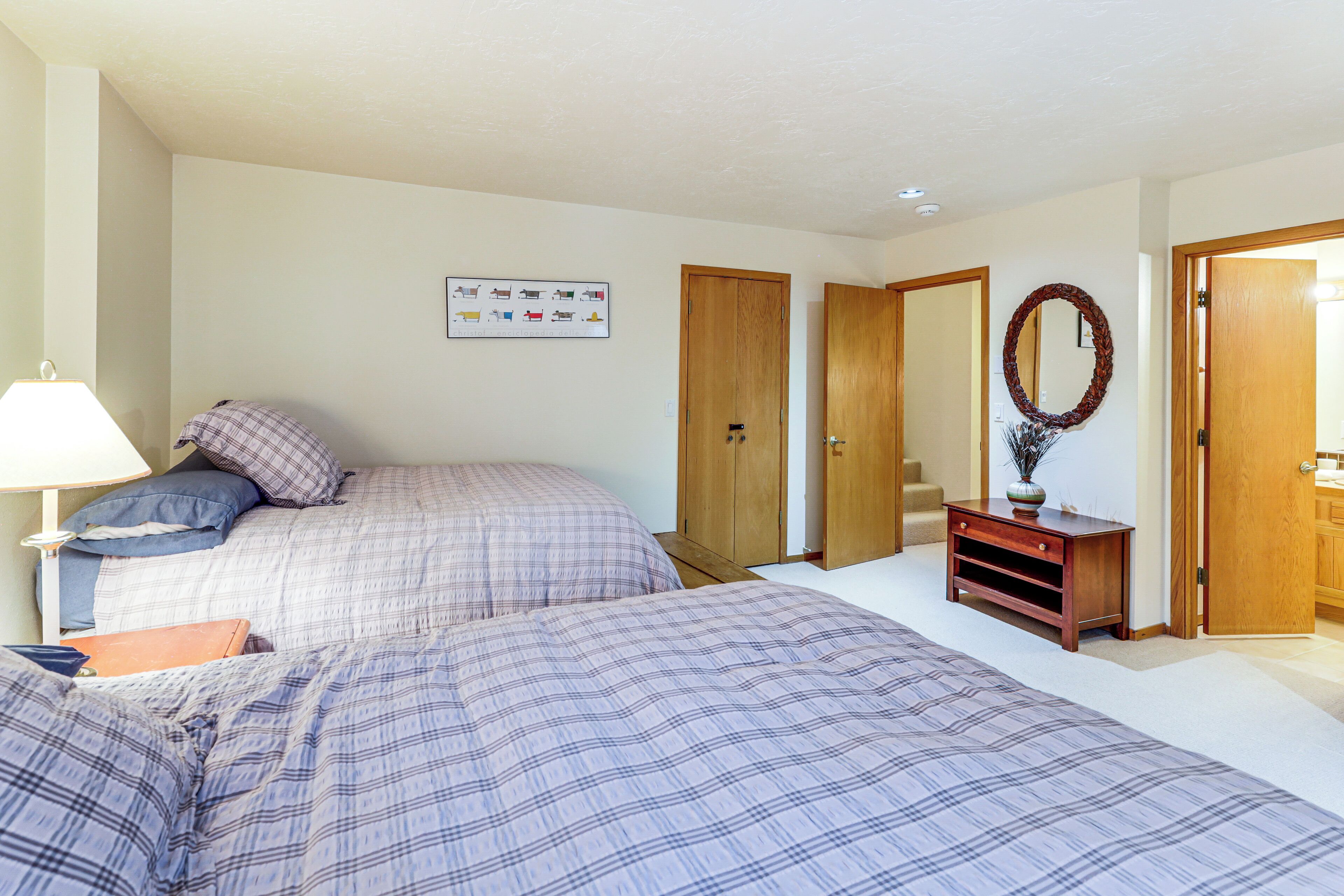A bedroom with two beds, a nightstand, a dresser, and a mirror.