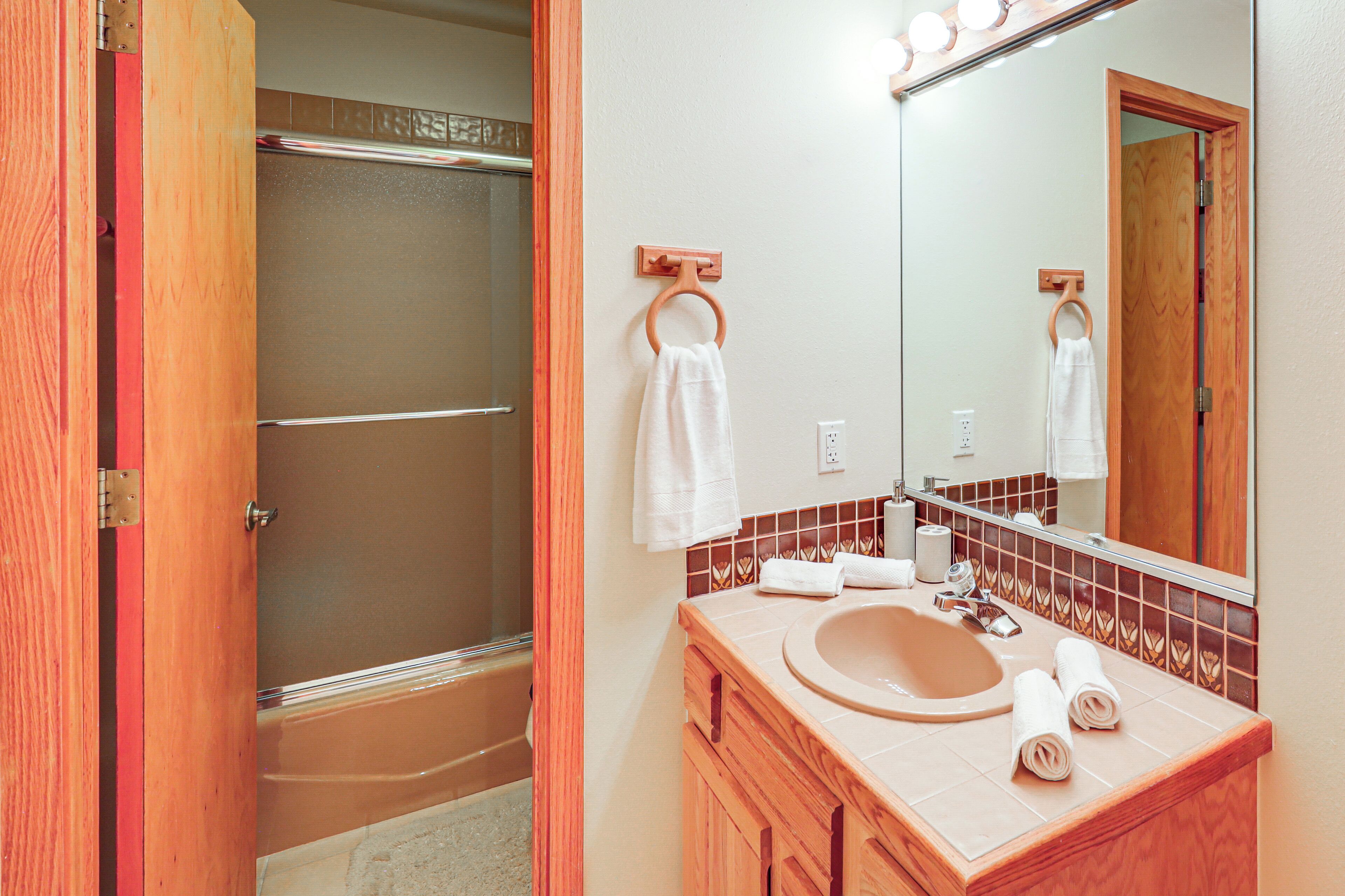 A bathroom with a wooden vanity, a sink, a mirror, and a shower.